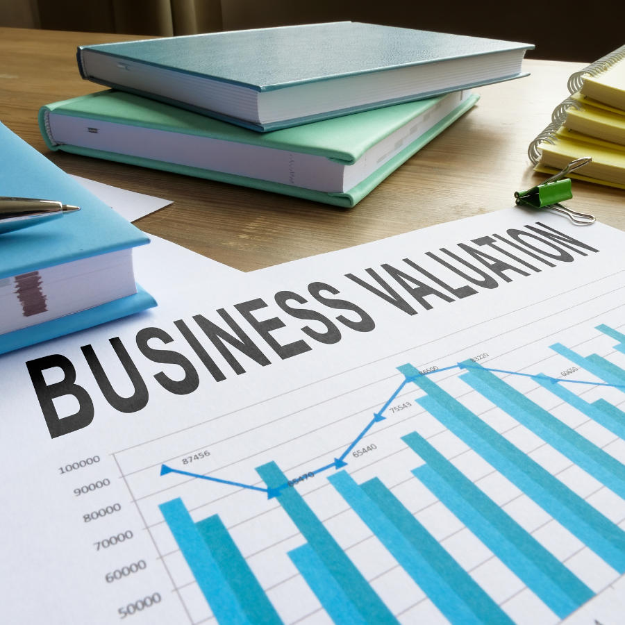 "Business Valuation" report with a bar and line graph on a desk with notebooks