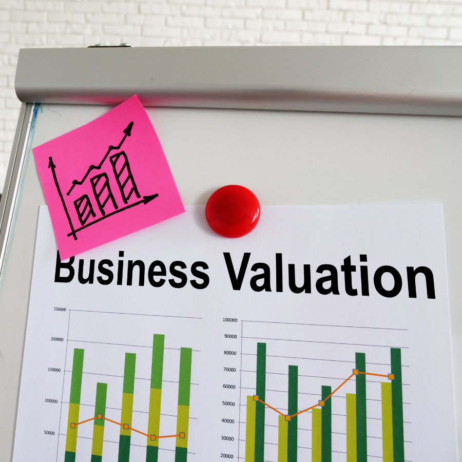 "Business Valuation" report on a whiteboard with a growth chart sticky note and red magnet